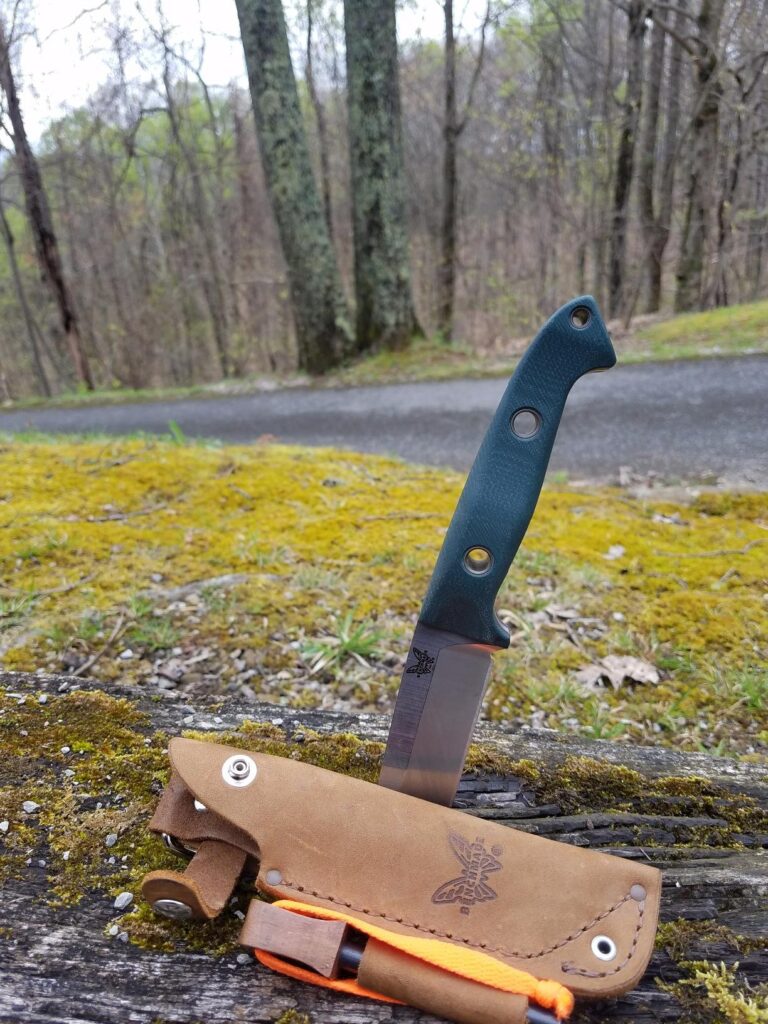 Best survival knife upright on a log in a field